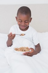 Pretty little boy eating cereals in bed 