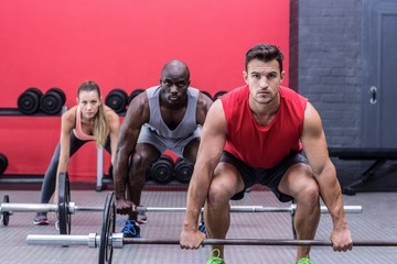 Fototapeta na wymiar Three muscular athletes lifting barbells