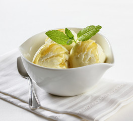 Vanilla ice cream with mint leaves in a bowl.