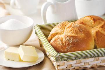 Buns for breakfast in a basket with sugar and butter