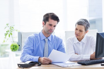 Obraz premium Two business people looking at a paper