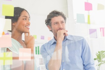Puzzled business team looking post its on the wall