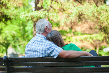 Senior couple sitting on bench in park, rear view