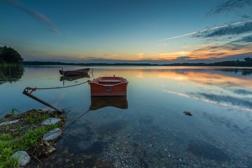Obraz premium Beautiful lake sunset with fisherman boat