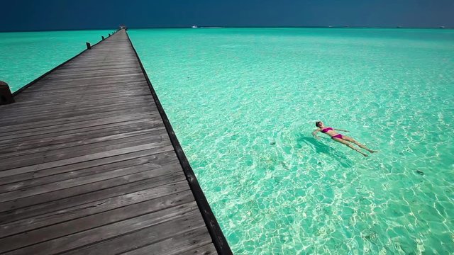 Young woman swimming in a coral lagoon next to jetty