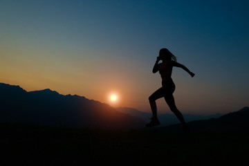 Silhouette of woman running at sunset in the mountains