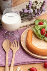 Breakfast with  sausage, salad vegetables and milk.