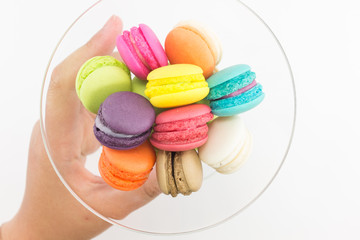 Colorful macaron with hand on white background.