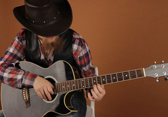 the young man with a red beard in a cowboy's hat sgitary in hands