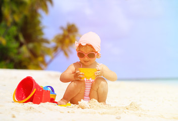 cute little girl playing with sand on the beach