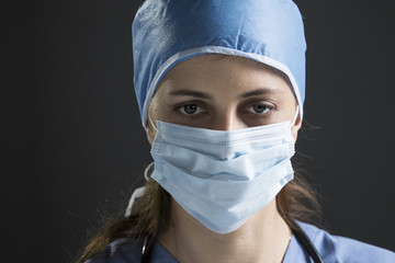 Female surgeon wearing surgical mask and cap, focus on her face