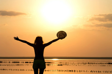 Fototapeta premium silhouette of a young girl on the sea in a hat