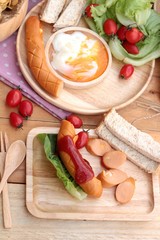 Breakfast with eggs, sausage, bread, salad vegetables and milk.