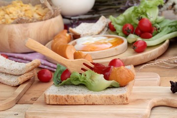 Breakfast with eggs, sausage, bread, salad vegetables and milk.