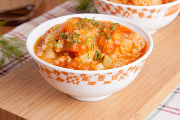 tomato soup with rice and vegetables in a white saucepan and bre