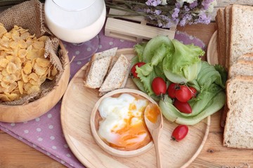 Breakfast with eggs, sausage, bread, salad vegetables and milk.