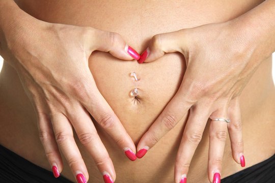 Hands make a heart shape on a pregnant belly