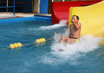 Young boy sliding down a yelow water slide