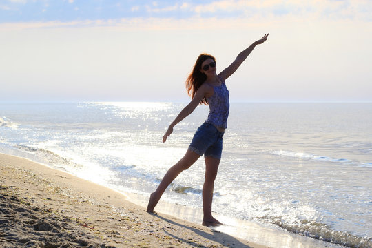 young slender woman doing gymnastics on the beach