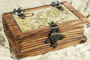 Wooden chest with a map on its cover, on the sand