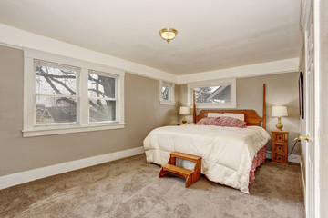 Very simple room with grey tan walls, and white bedding.