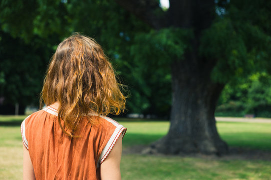 Young woman looking at tree in park