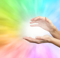 Rainbow healing energy field - Female outstretched healing hands on soft rainbow energy background