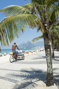 Brazilian man rides cart delivering fresh ice to beach stalls along the Ipanema Beach boardwalk at Arpoador