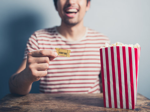 Happy man with popcorn and cinema ticket