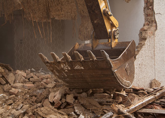 A large track hoe excavator tearing down an old house