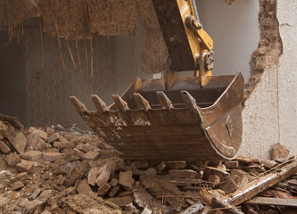 A large track hoe excavator tearing down an old house