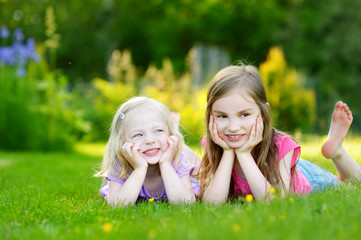 Two cute little sisters having fun on the grass