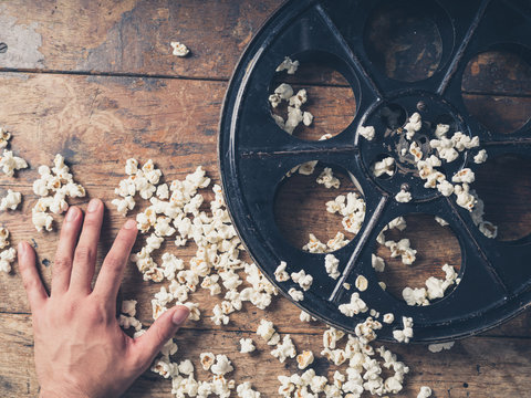 Hand with film reel and popcorn