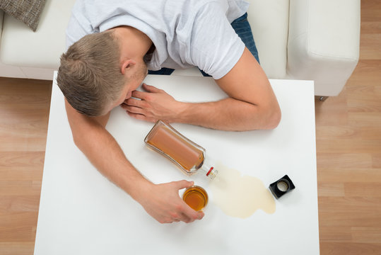 Drunk Man Sleeping On Table With Alcohol