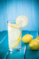 Fresh lemonade with lemon on wooden background