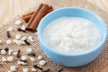 Brazilian dessert canjica of white corn with cinnamon in blue bowl. Selective focus