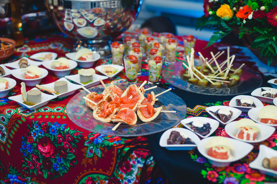 Beautifully decorated catering banquet table with different food snacks and appetizers with sandwich, caviar, fresh fruits on corporate birthday party event or wedding celebration 