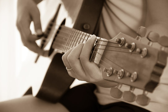 Woman playing acoustic guitar, sepia tone