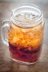 Glass of cola with ice on wooden table