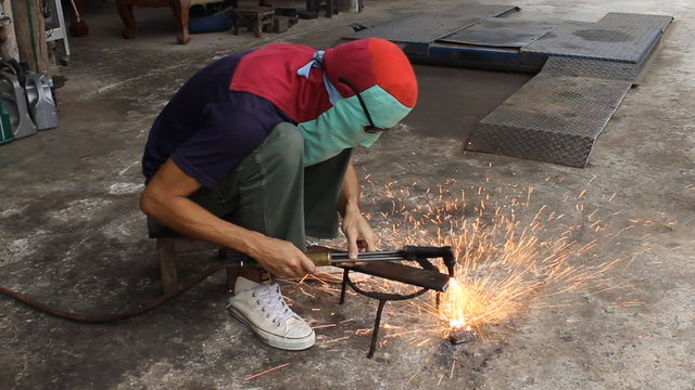 Metal cutting with Acetylene gas. Workman is cutting metal plate by use Acetylene gas. Spark splash around the ground.