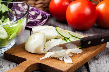 Chopped vegetables: onion and cucumber on cutting board