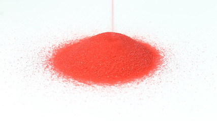 Red sand are slowly falling. Strewing red sand.