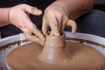 Hands working with clay on potter's wheel