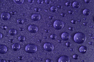 Water drops on the violet surface. Selective focus.