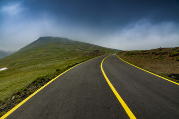 High altitude road into the mountains in foggy day