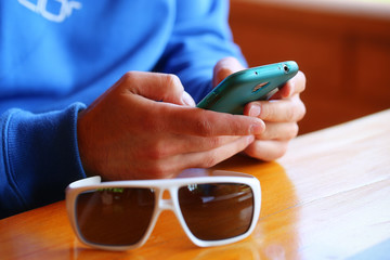 man with sunglasses sitting in a restaurant and playing on a sma