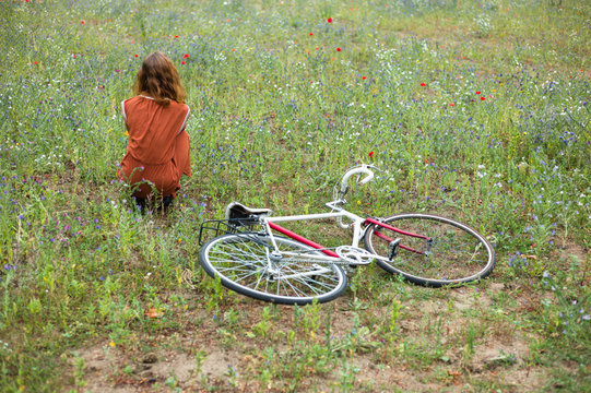 Woman sitting in meadow with bicycle