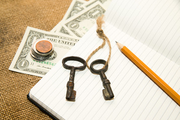 Opened notebook, pencil, key and money on the old tissue