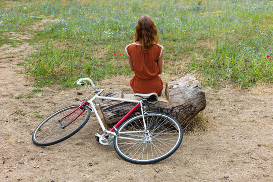 Woman sitting on log with her bike