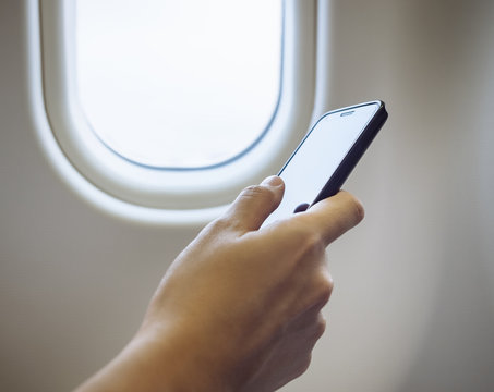 Woman Hand Using Cell Phone In Airplane